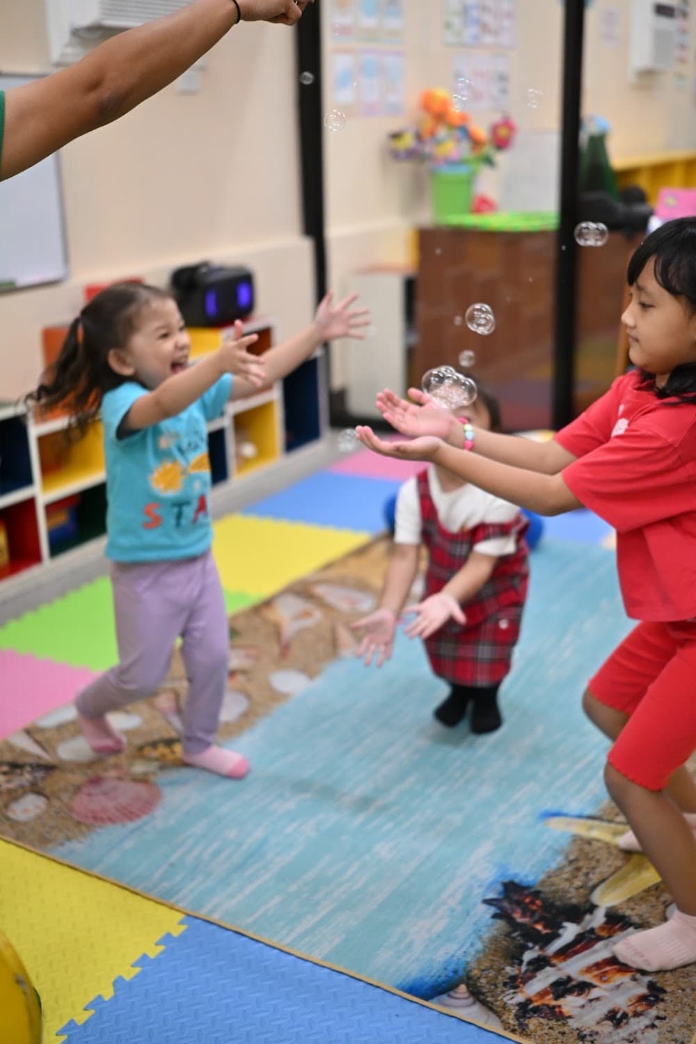 Children laughing and reaching for soap bubbles
