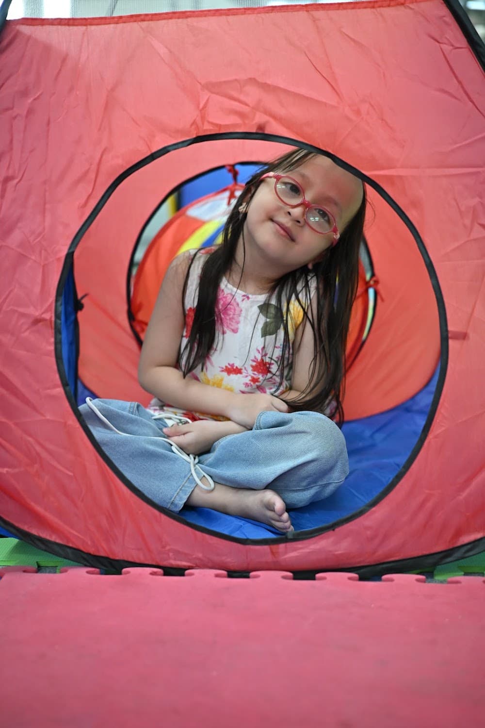 A girl sitting inside a colorful play tunnel